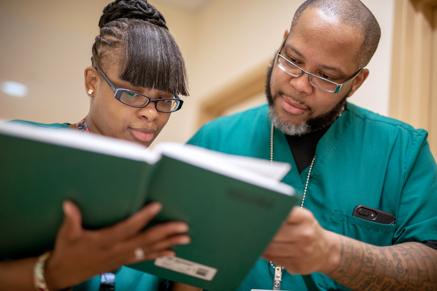 BronxCare Health and Wellness Center Medical Assistants, Ebony Simmons and Aaron Martinez, reviewing patient log book.