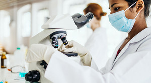 Stock photo of epidemiologist viewing microscope